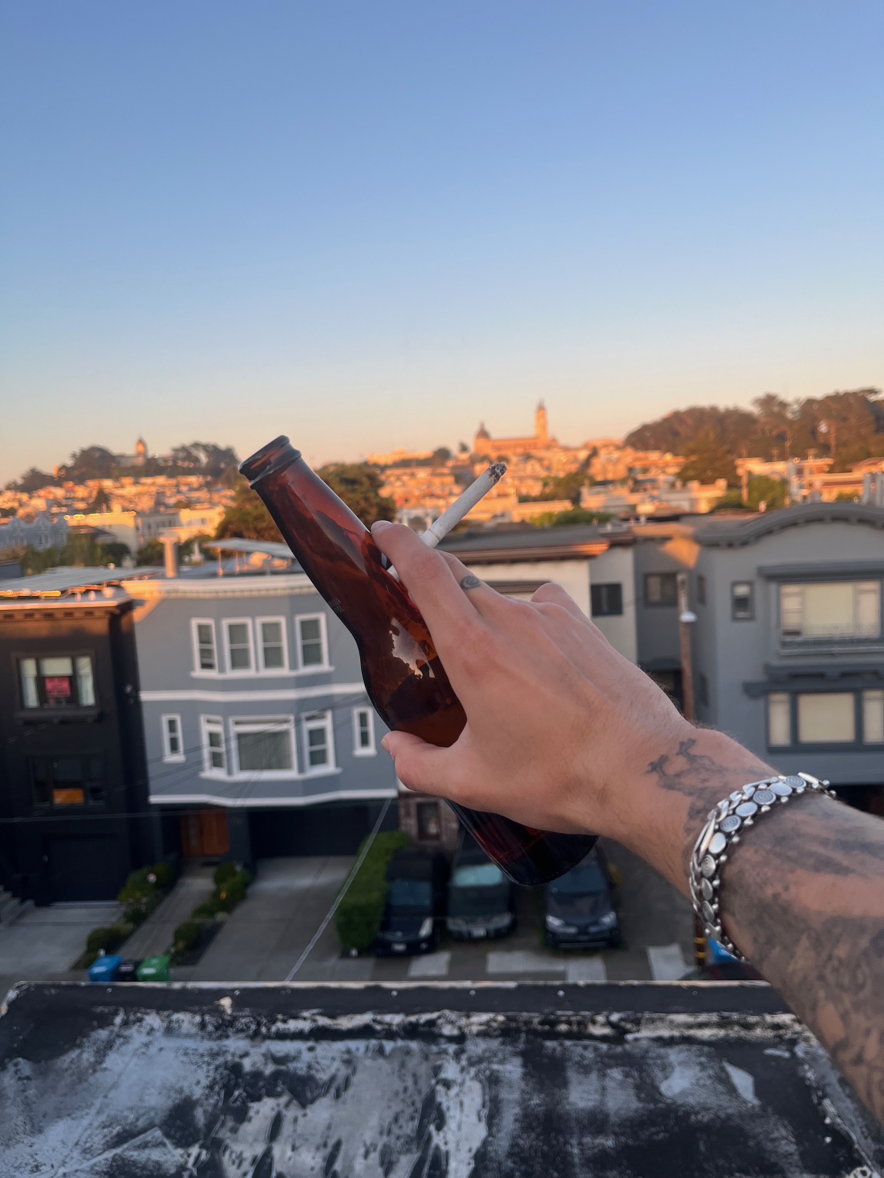 holding a beer and cig with the sunset in the background