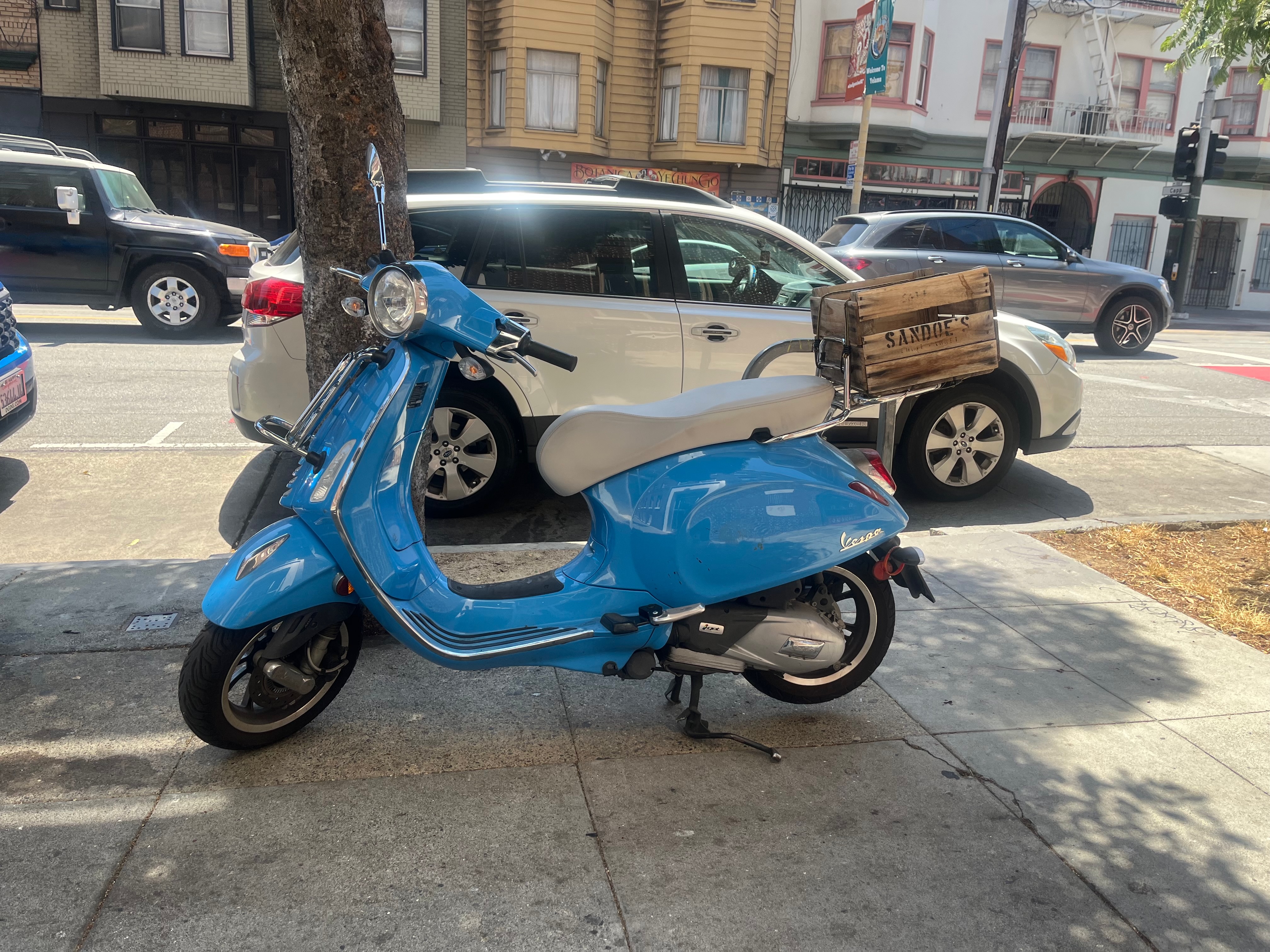 blue vespa parked on the sidewalk